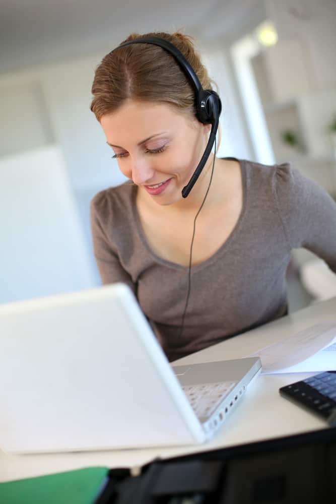 woman using laptop with headset figuring out how can a stay at home mom make money online