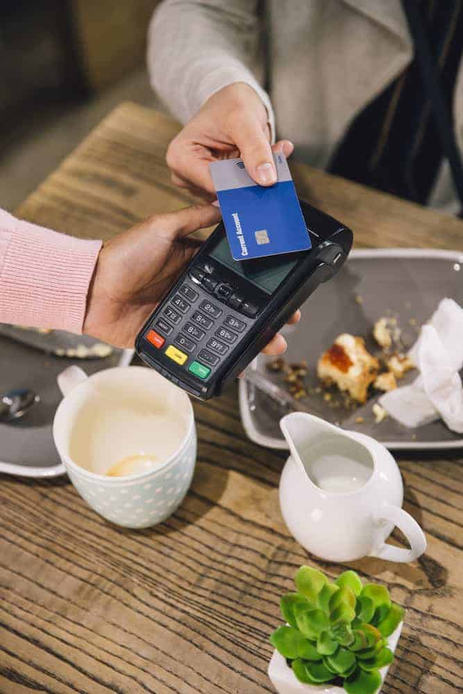 person using new replacement debit card at cafe