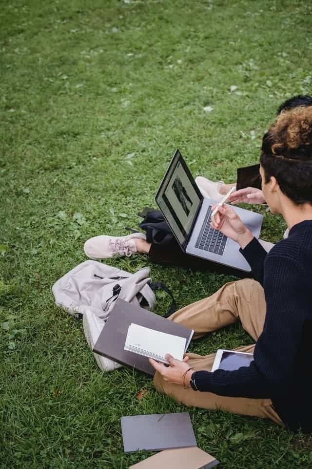 college students sitting on grass working out what to cut from your budget