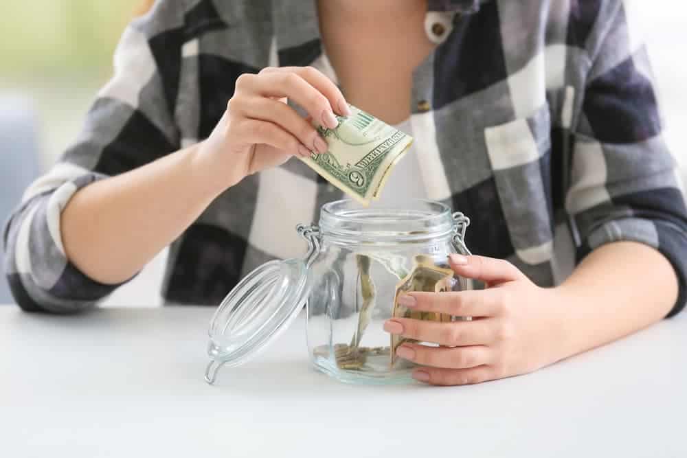 woman putting money in jar as a way to make $20 instantly daily, fast and free