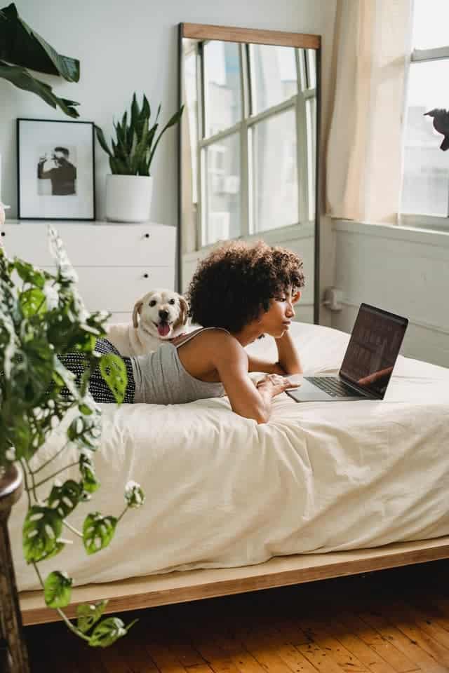 woman lying on her bed working on her laptop to make $200 a day fast