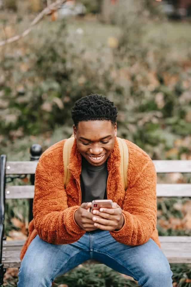man smiling while using his phone