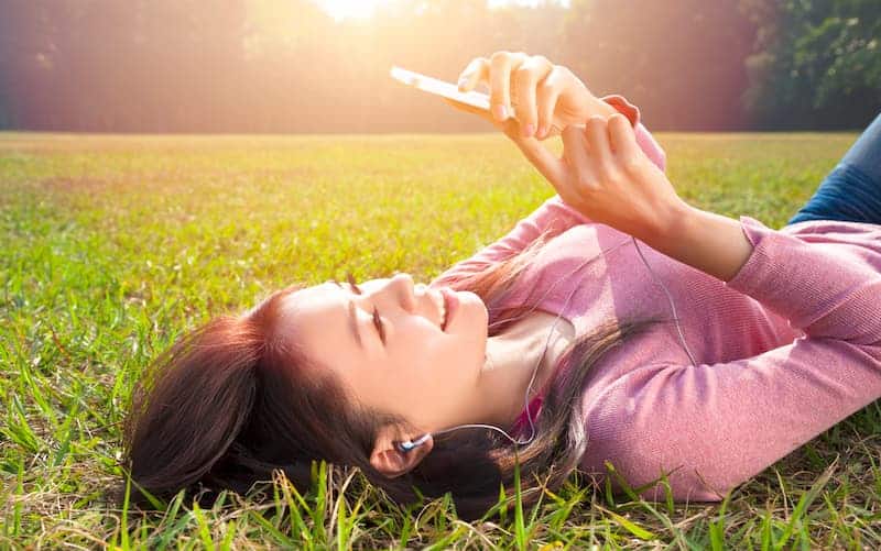 woman lying on grass doing a mistplay review with her phone to see if the mistplay app is legit