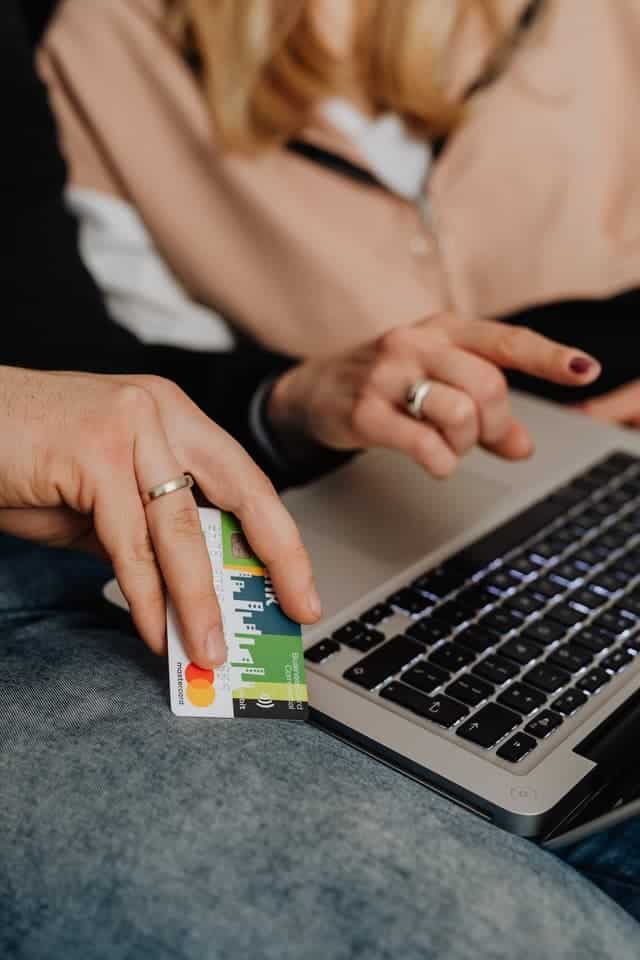person holding a bank card while using a laptop