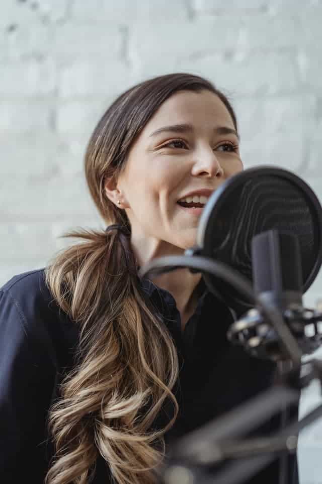 woman speaking into a microphone for a voiceover job with no experience needed
