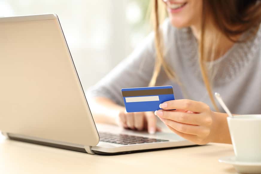 woman using her laptop holding a bank card