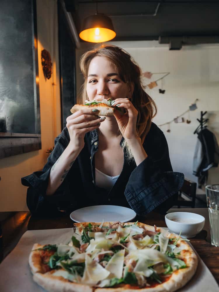 A woman in a restaurant getting paid to eat a pizza