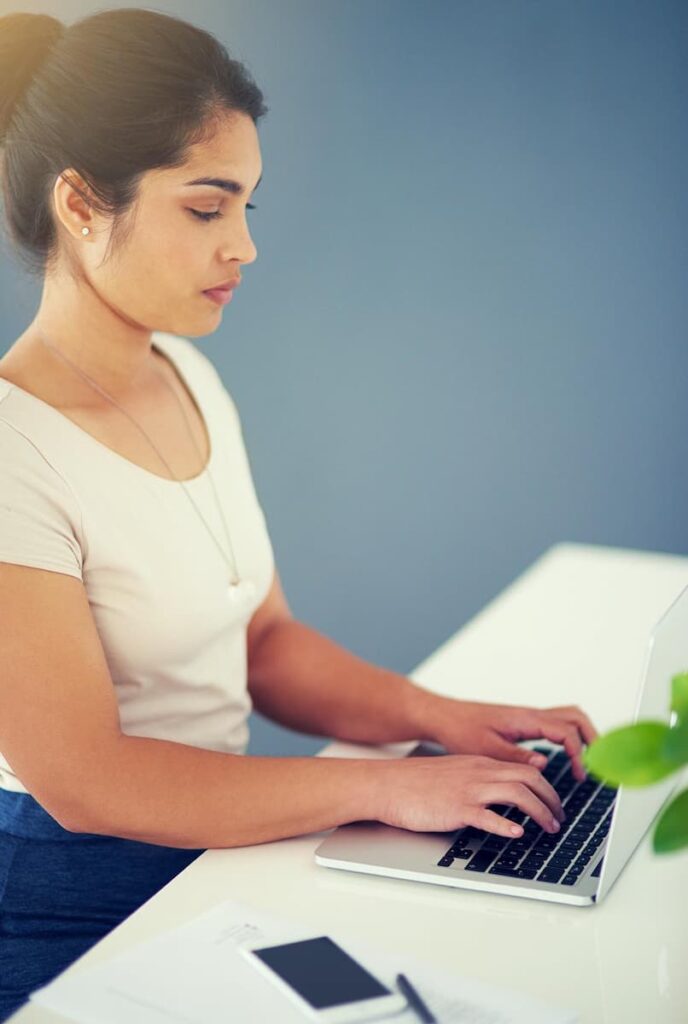 a woman typing on her laptop using the best blog fonts