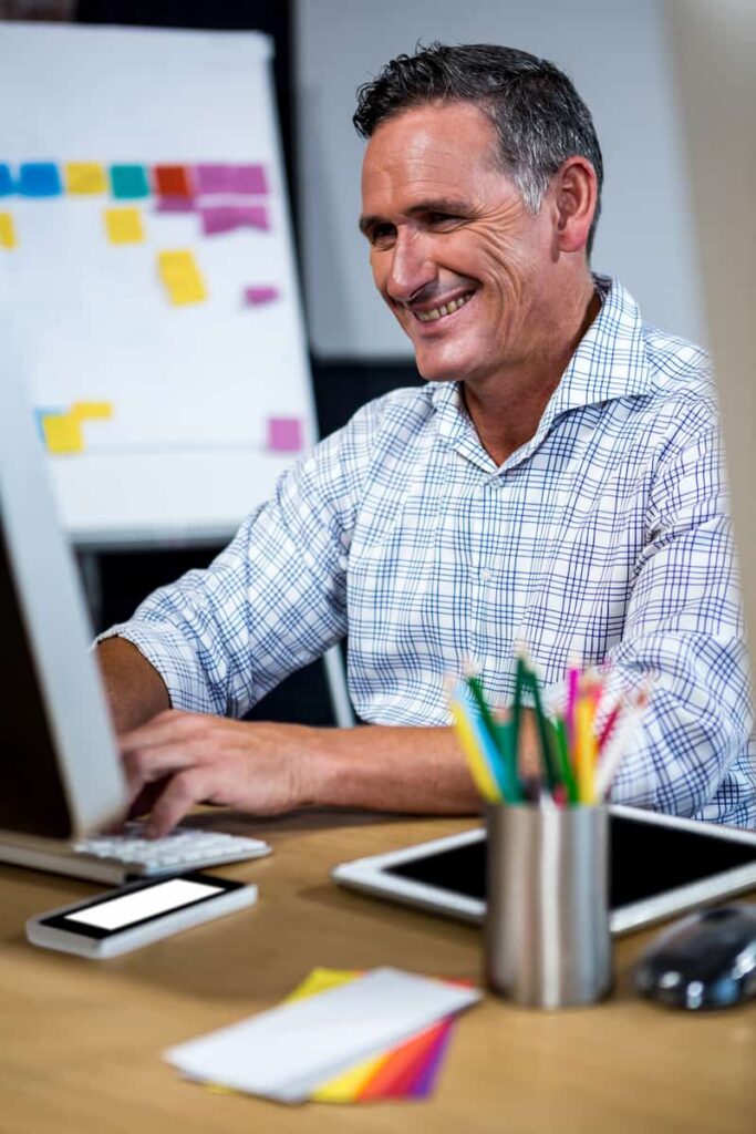 a man smiling in front of his computer selling digital downloads on etsy