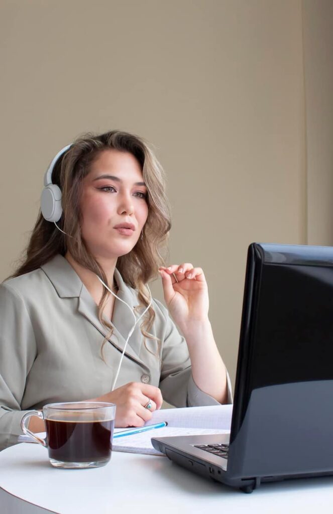 a woman with headphone in front of a computer working in one of the best transcription jobs from home with no experience