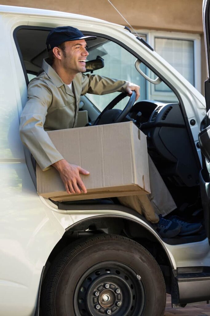 a delivery man holding a box getting out of the vehicle
