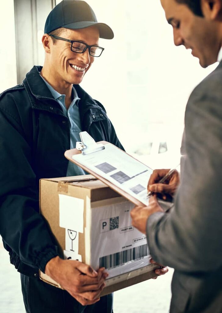 a delivery man holding a package while the customer is signing a document