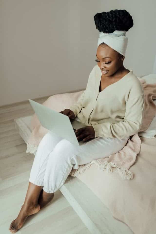 a woman sitting on the bed with her laptop