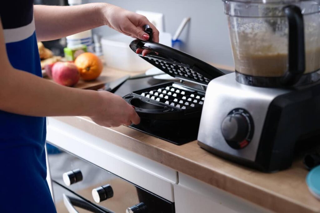 a woman using a used waffle maker 
