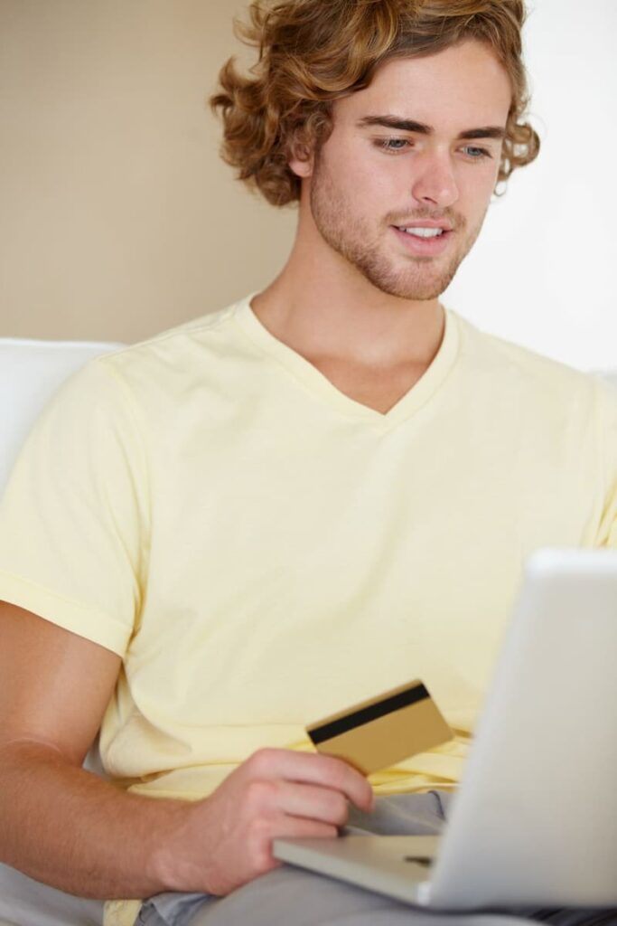 a man holding a debit card and searching for Chime routing number on his laptop
