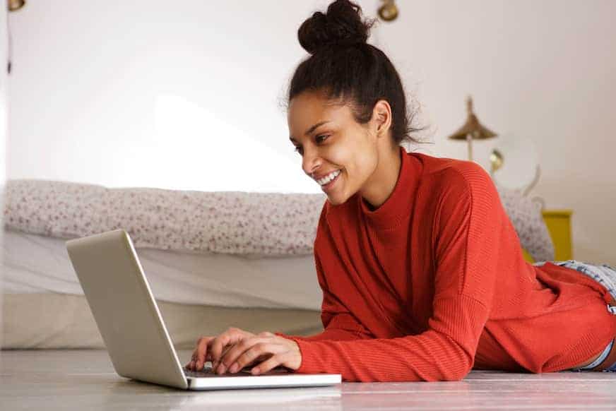 a woman typing on her laptop to get paid to be a virtual friend
