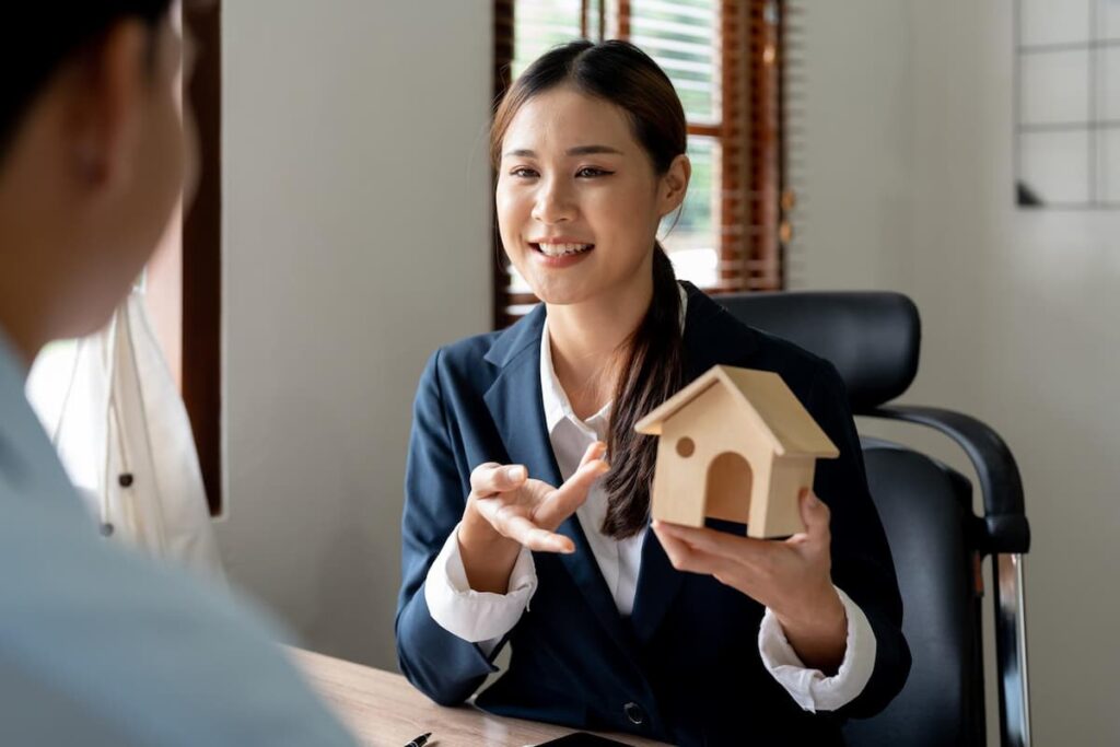 a woman with the best paying job in real estate investment trusts holding a house model talking to a client
