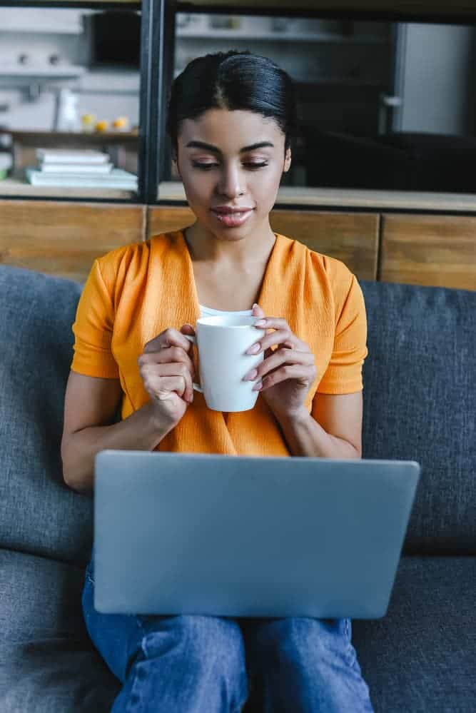 a woman holding a mug and laptop 