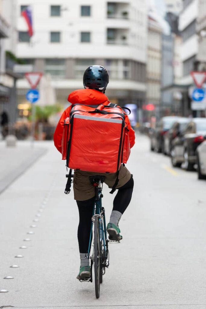 a man riding a bicycle working as a DoorDash delivery driver
