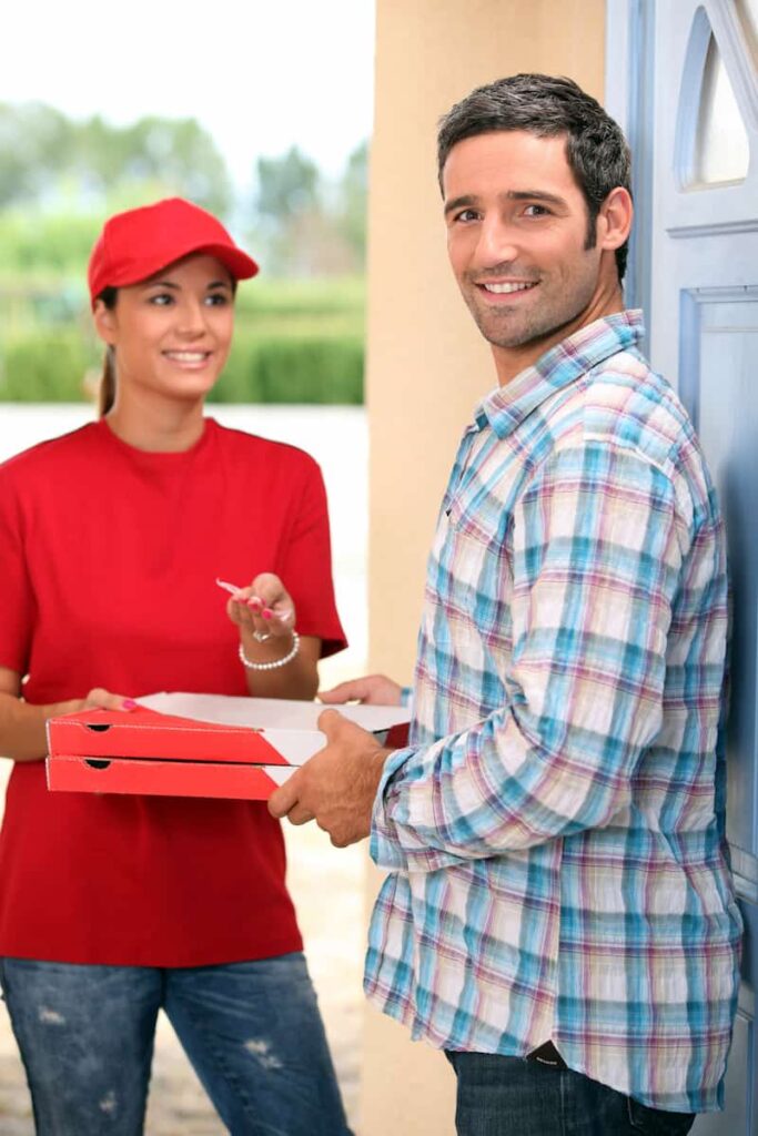 a delivery woman holding boxes of pizza with her customer 