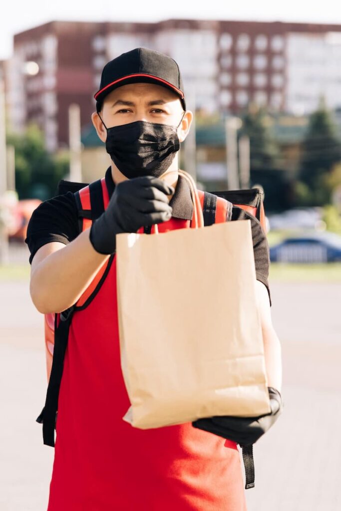 a man wearing a face mask with bag working as a DoorDash delivery driver