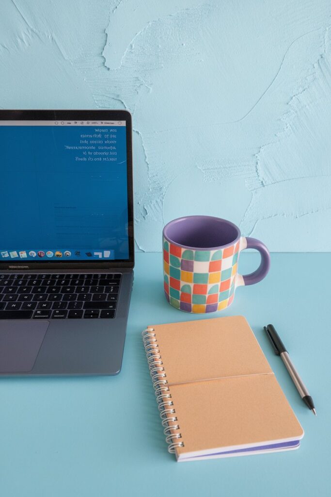 Flatlay of laptop, coffee, notebook, and pen
