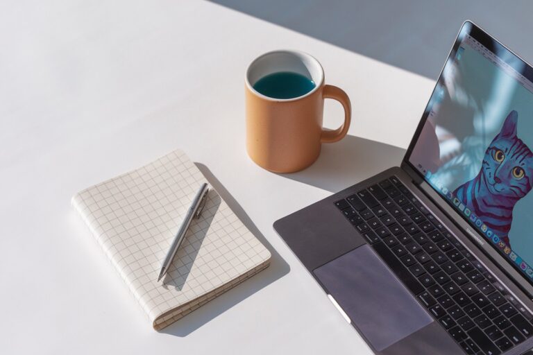 a laptop and notebook workspace setup being used by someone to make $3,000 a month