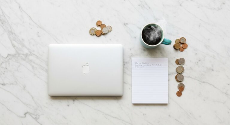 a flatlay of a laptop and teal mug on a marble surface for selling on Etsy