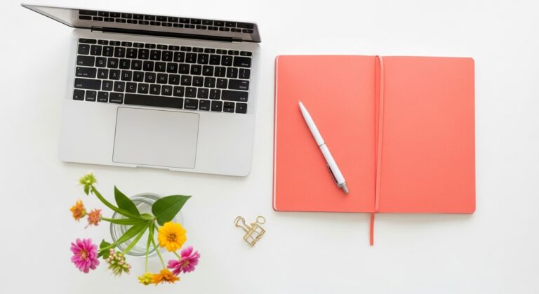 a flatlay with laptop and other items on a white surface for selling on Etsy
