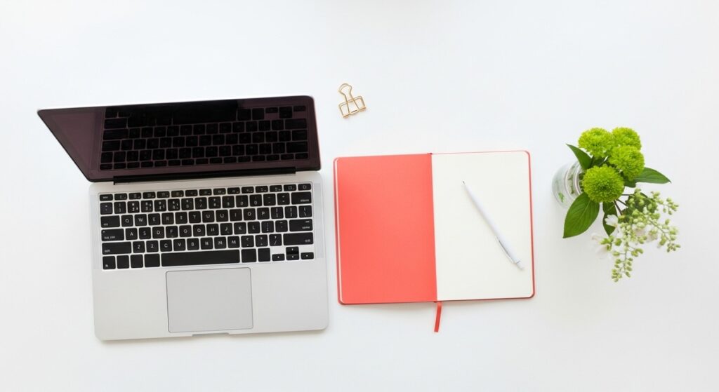 a flatlay with laptop and other items on a white surface for saving money