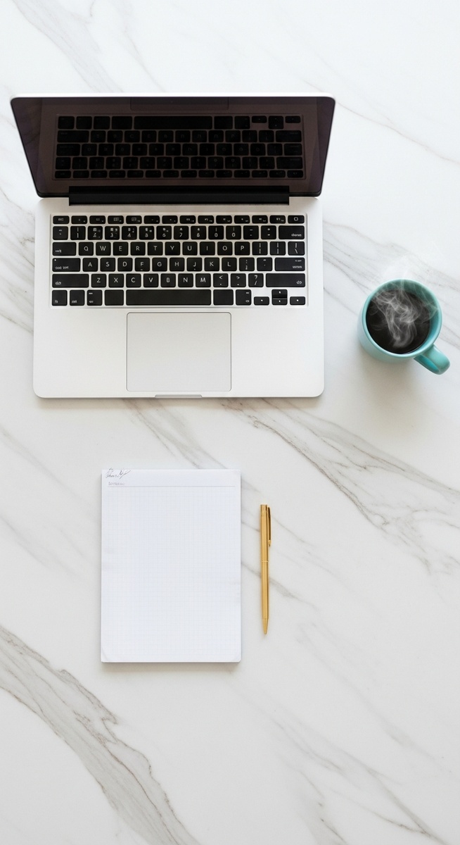 a flatlay of a laptop and teal mug on a marble surface for selling on Etsy