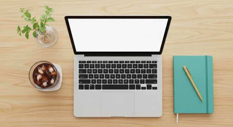 a flatlay of a laptop and teal notebook on a wooden desk for typing jobs