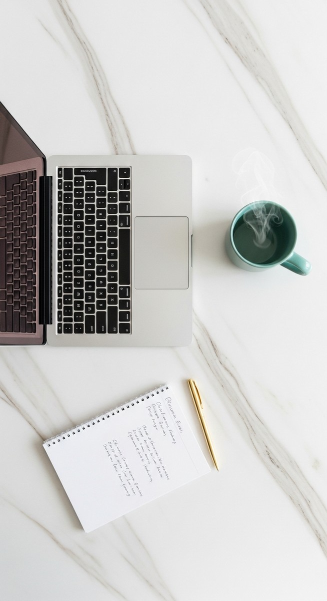 a flatlay of a laptop and teal mug on a marble surface to make money