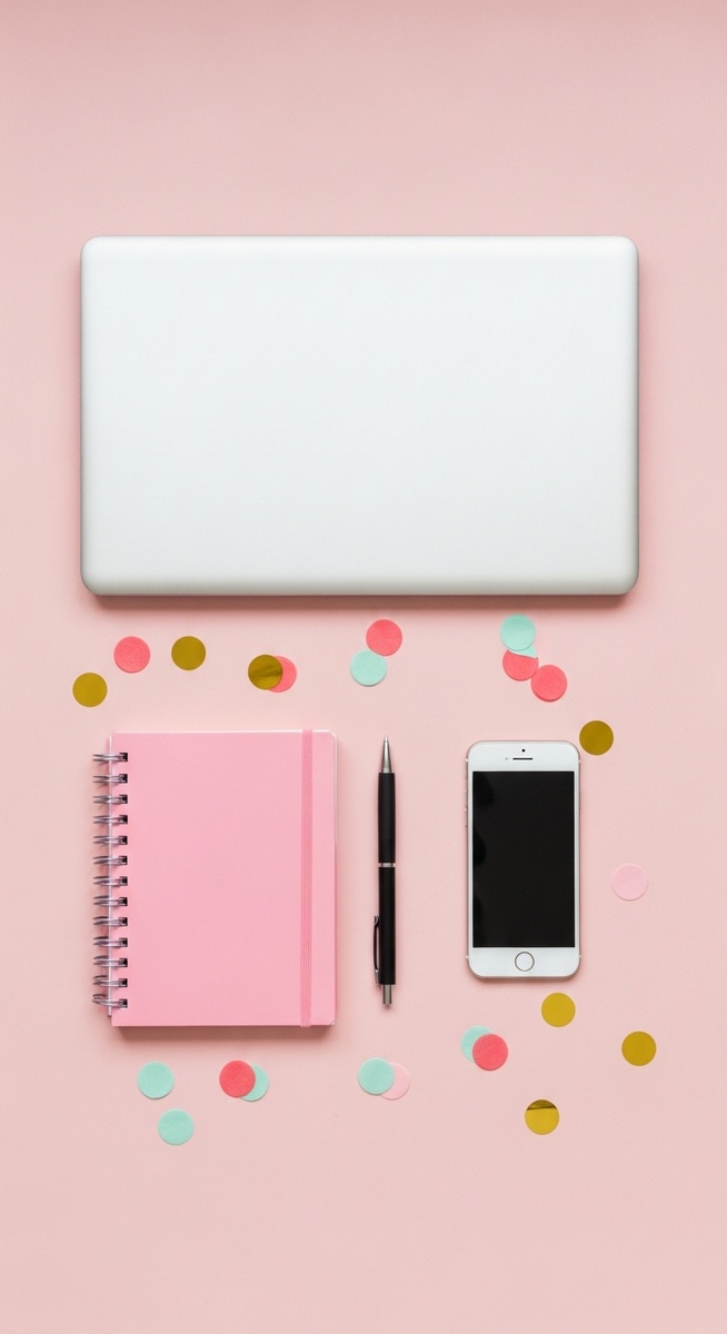 pink flatlay with laptop, notebook, and phone
