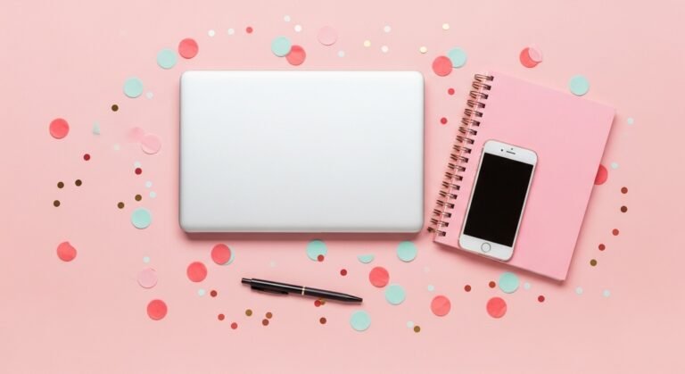 a pink flatlay with laptop, notebook, and phone to invest money