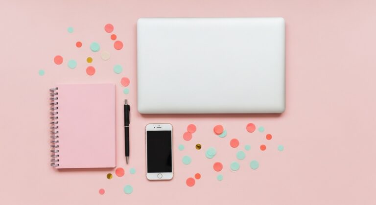 pink flatlay with laptop, notebook, and phone