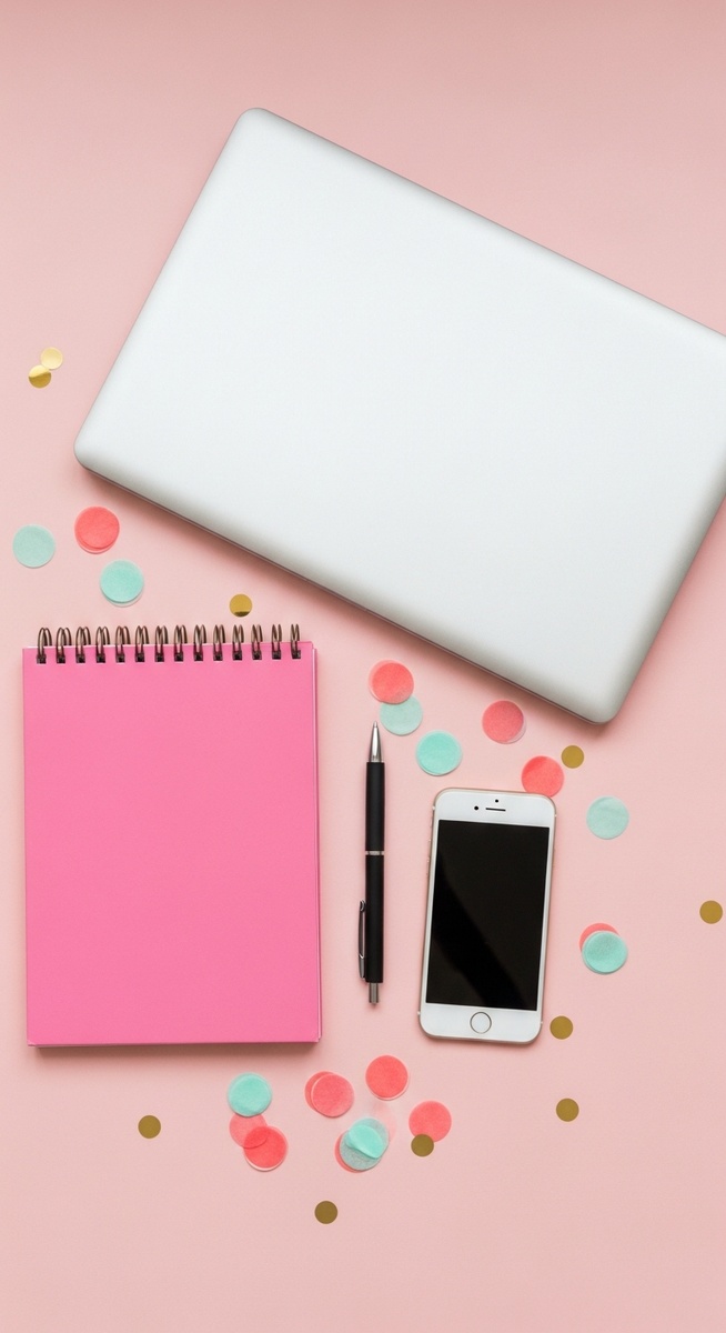 a pink flatlay with laptop, notebook, and phone for stay-at-home moms