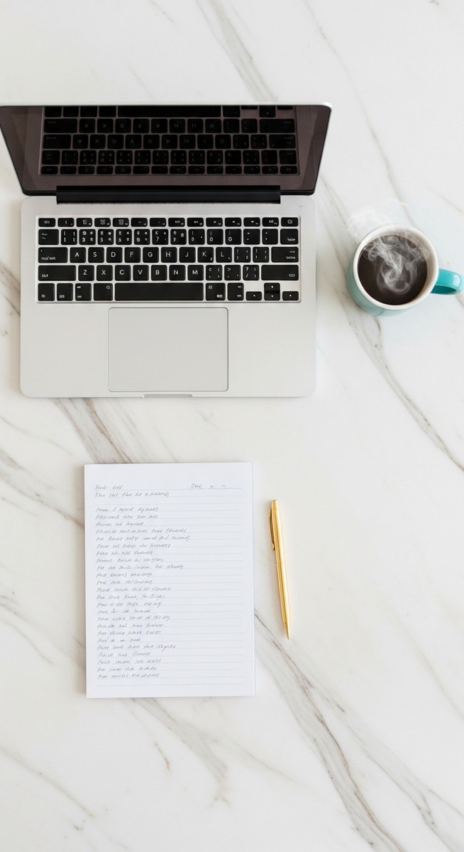 a flatlay of a laptop and teal mug on a marble surface to make money