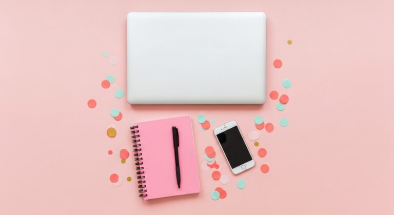 a pink flatlay with laptop, notebook, and phone for earning with surveys